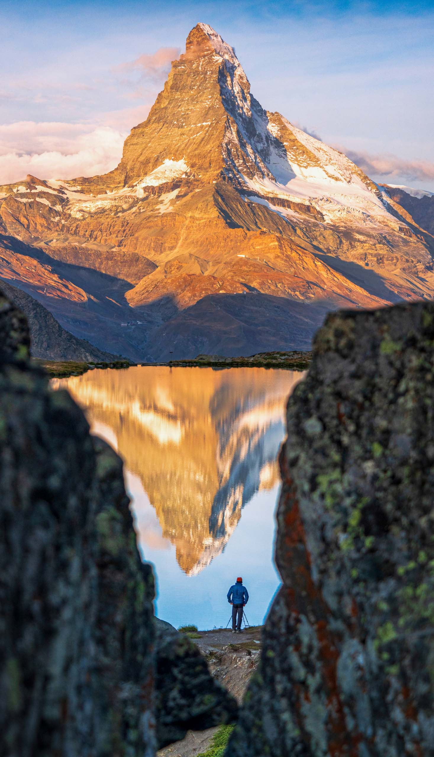 Man photographing Matterhorn from lake Stellisee at dawn.