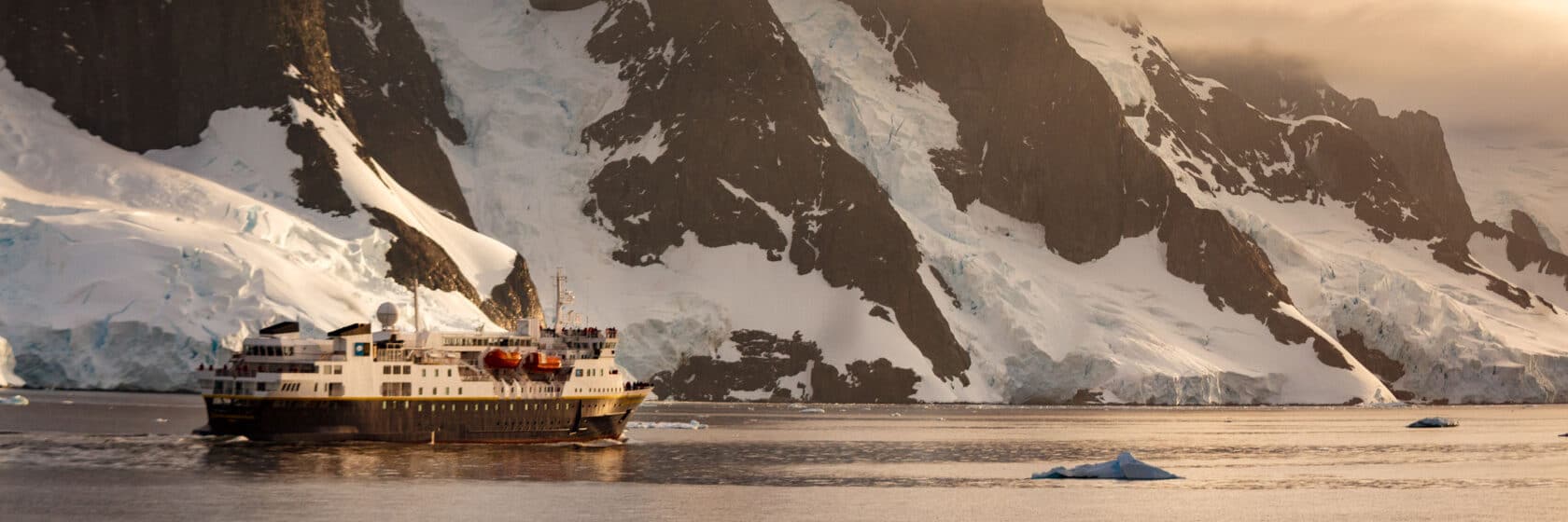 An expedition ship cruises along the Lemaire Channel, Antarctica.