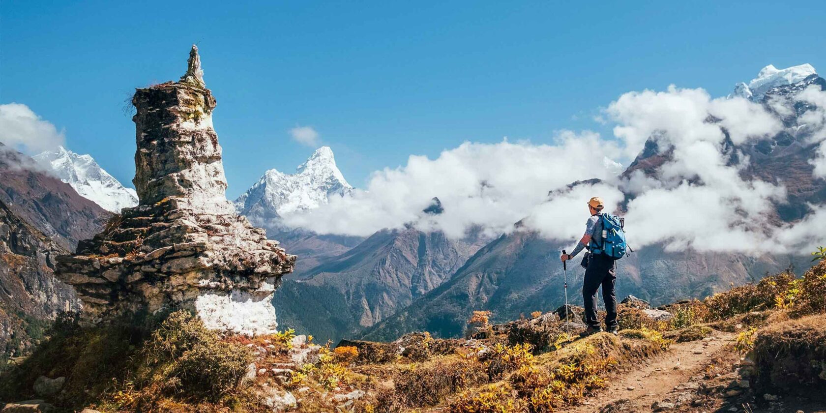 A backpacker man with trekking poles enjoying the Ama Dablam peak.