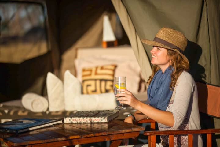 A woman enjoying a beverage outside a tent.