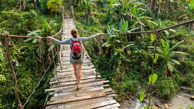 A woman walking on a footbridge in tropical rain forest in Costa Rica.