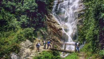 Hikers crossing a stream by the waterfall below Winay Wayna in Peru.