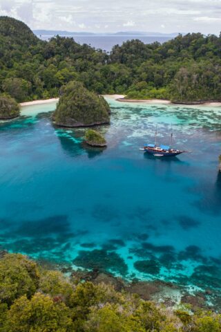 Rugged limestone islands surround a beautiful, tropical lagoon in Raja Ampat, Indonesia.