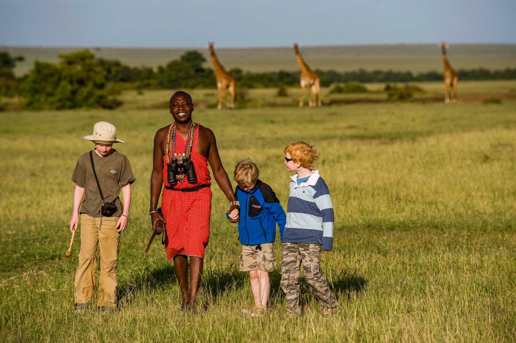 A safari guide guiding three boys in Kenya.
