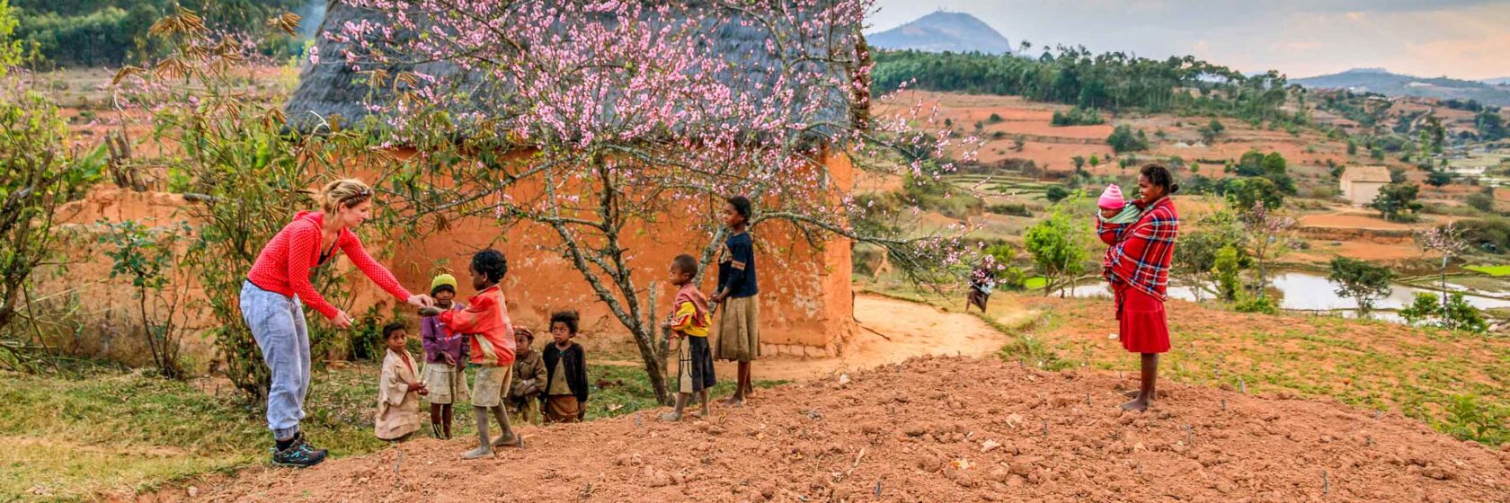 Tourist meets local children near flowering tree in Madagascar.