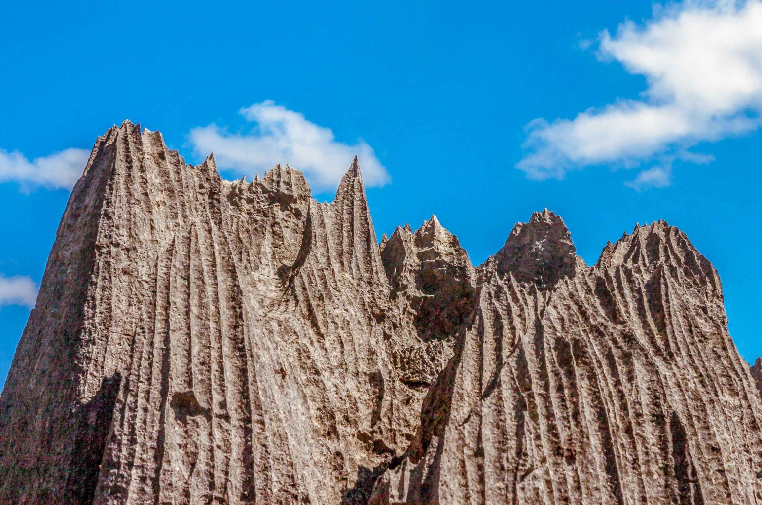Tsingy limestone pinnacles rise in front of blue sky in Madagascar.