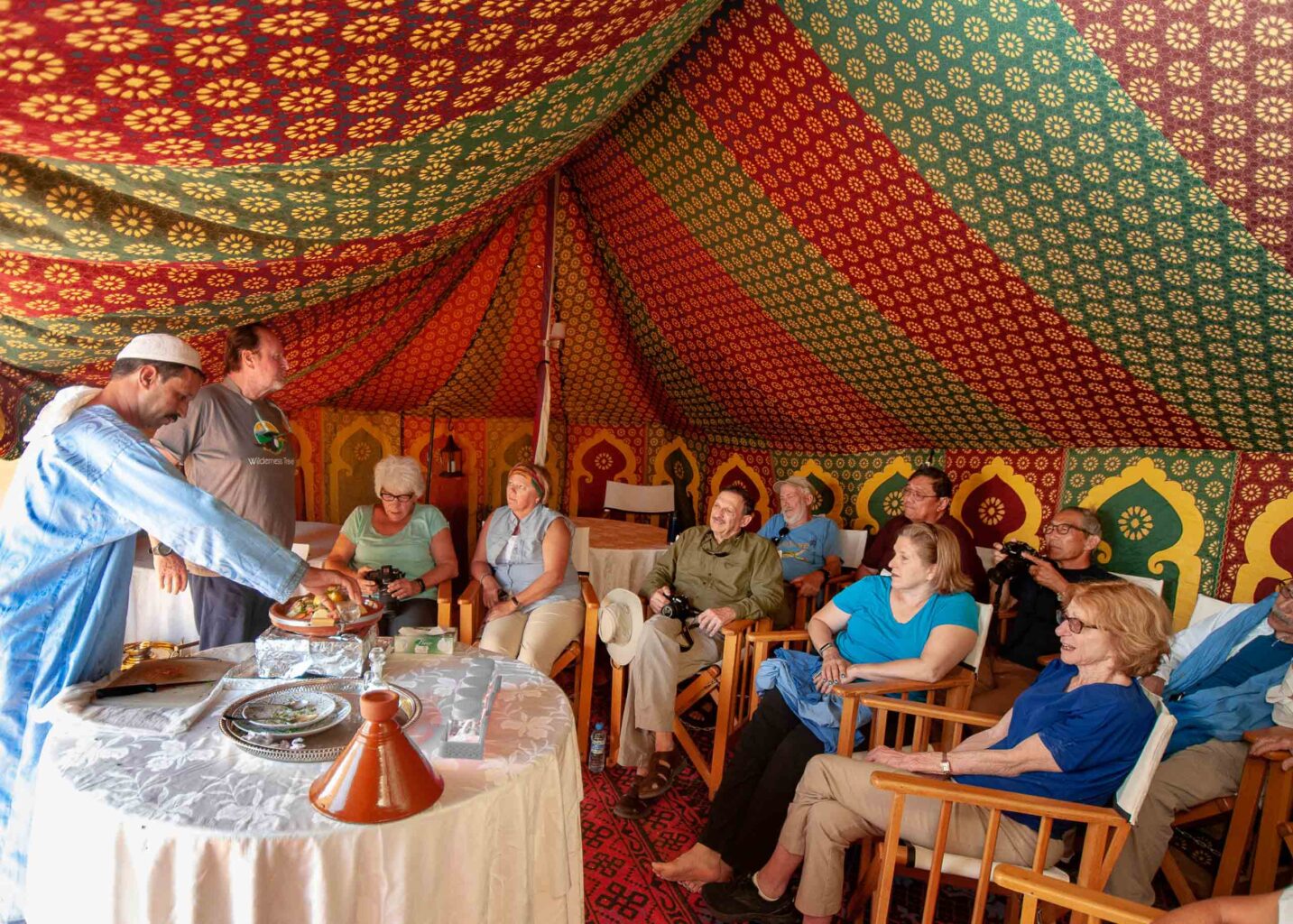 Eight travelers prepare to dine in an exotic Moroccan tent in the Sahara Desert.