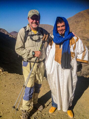 A hiker and a person wearing traditional Moroccan clothing.