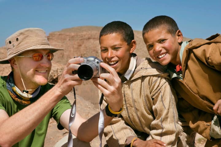 A tourist showing two children his camera.