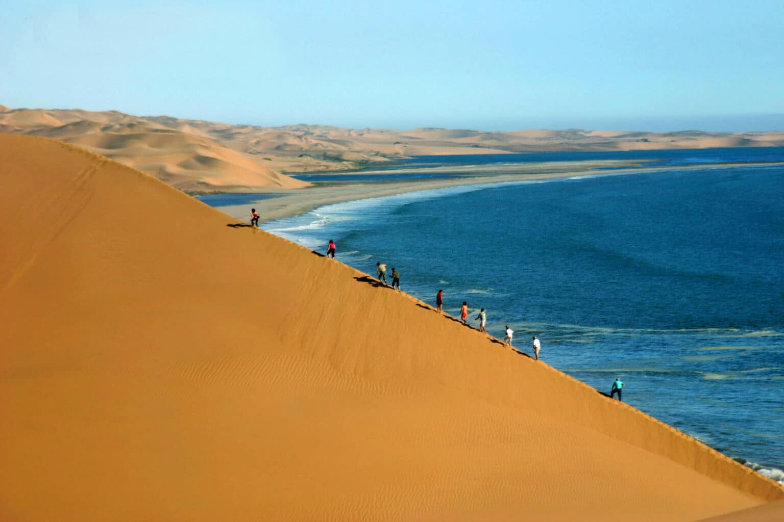 A group of people climbing dunes in Namibia.