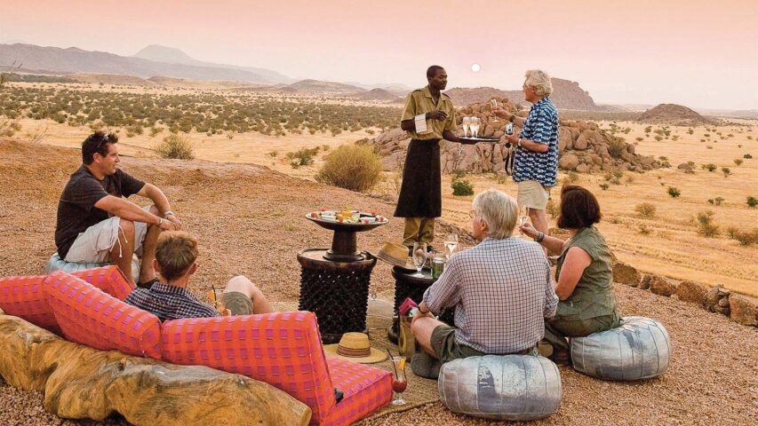 A group of tourists enjoying food and drinks outdoors in Namibia.