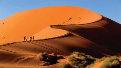 Tourist climbing the red dunes in Namibia.