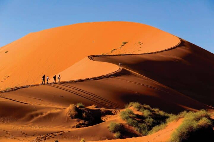 Tourist climbing the red dunes in Namibia.