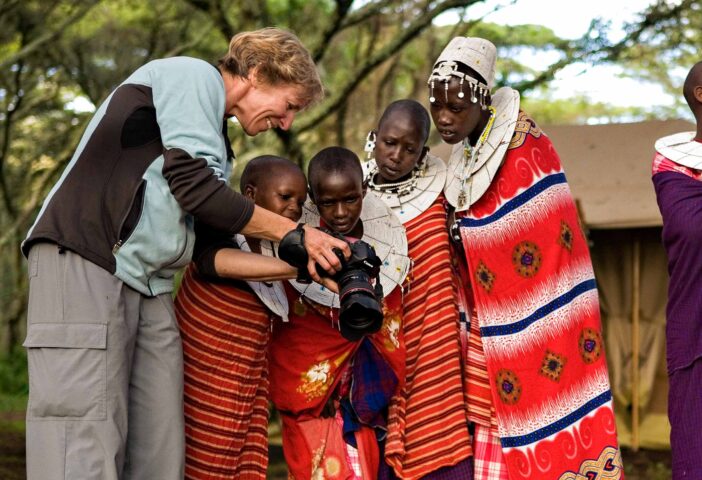 A photographer showing her camera to local children in Tanzania.