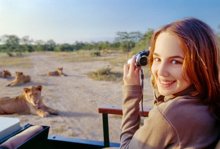 A tourist using binoculars to observe lions in Tanzania.