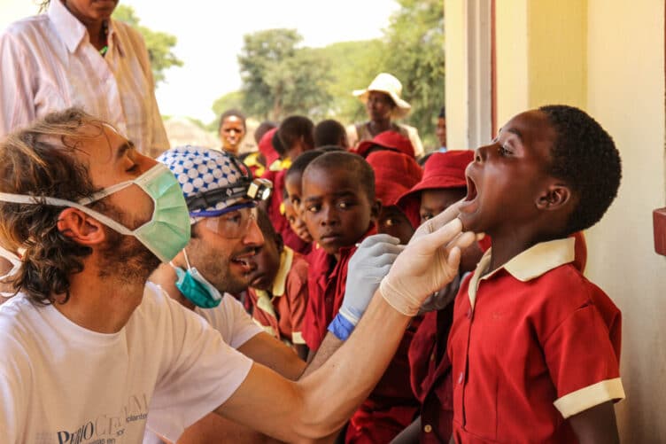 Dentists checking teeth of children in Zimbabwe village.