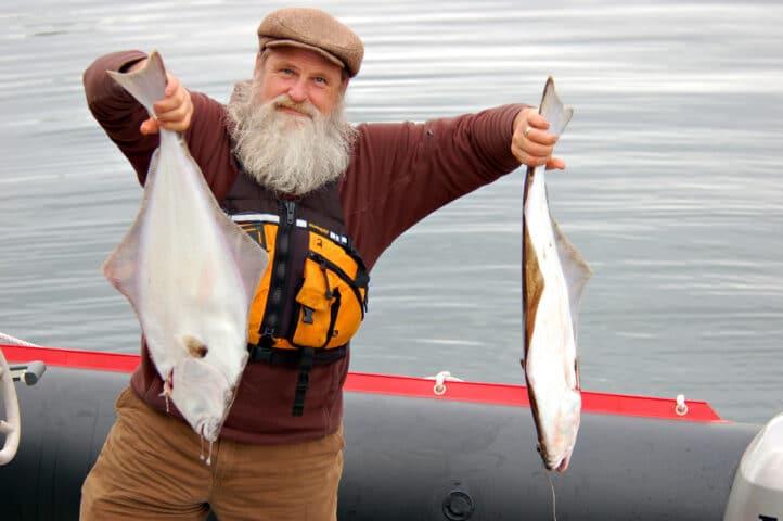 A fisherman holding two fish.