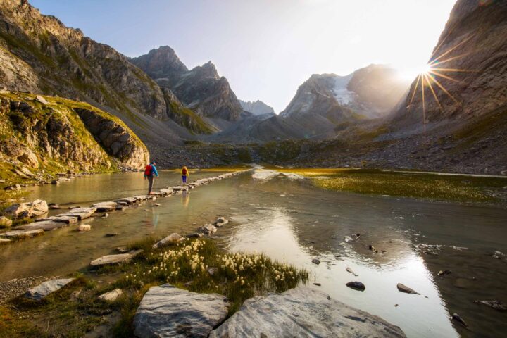 Hikers crossing a stone path in the Alps.