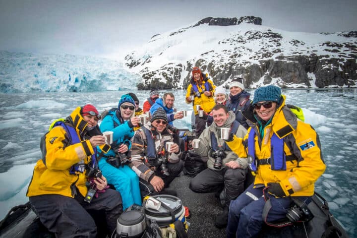 A group of tourists enjoying a drink together in Antartica.