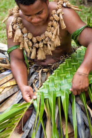 A Fiji man weaving with palm leaves.