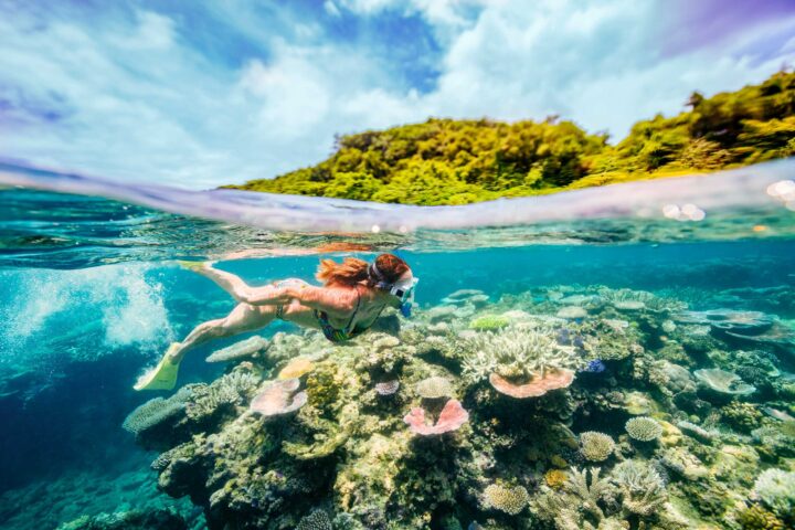 A woman snorkeling past a coral reef.