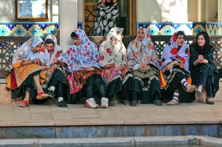 Six Iranian women wearing traditional floral headscarves.