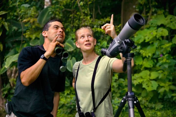 Pretty Woman with Binoculars and Man with Telescope in Jungle