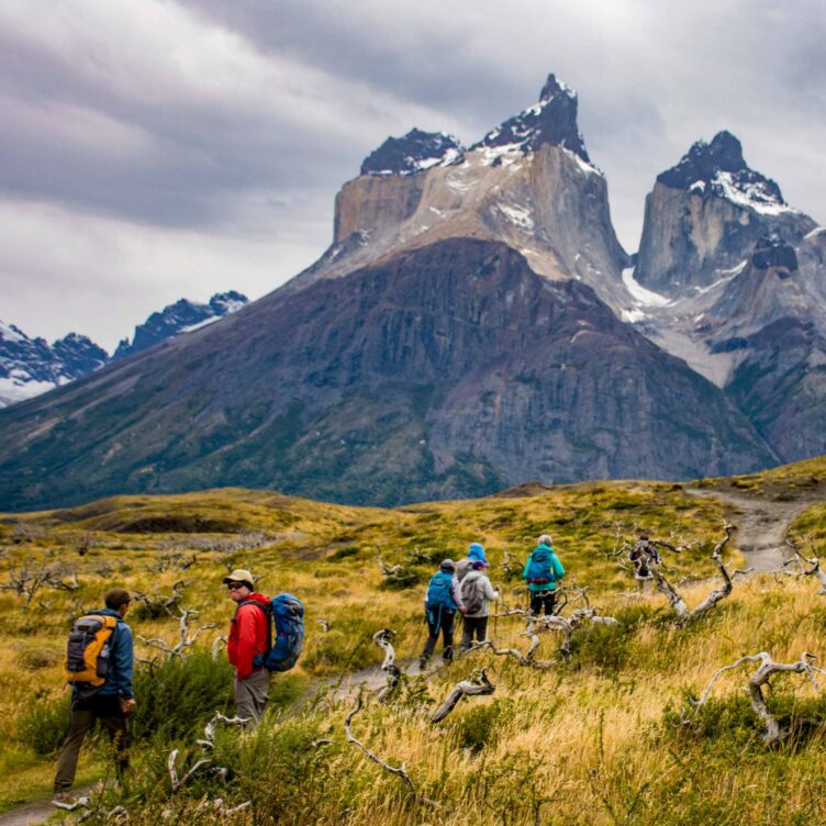 A group of hikers on a trail towards mountains in Patagonia.