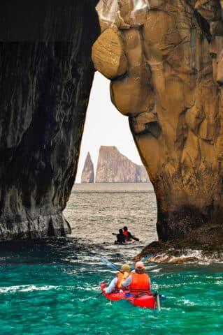 Latin America South America Ecuador Galapagos Islands San Cristobal Island Group of sea kayakers paddle through cave on Cerro Br