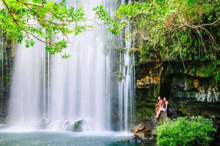 Two woman relaxing next to a waterfall.