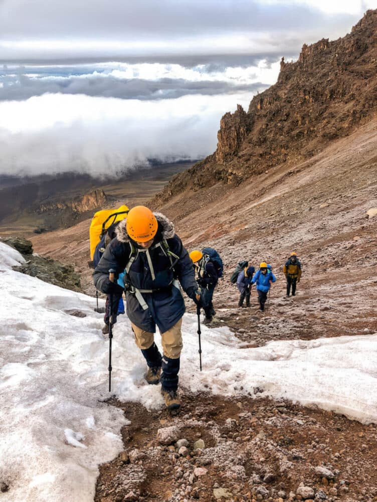 Hikers climbing through snow on Mount Kilimanjaro.