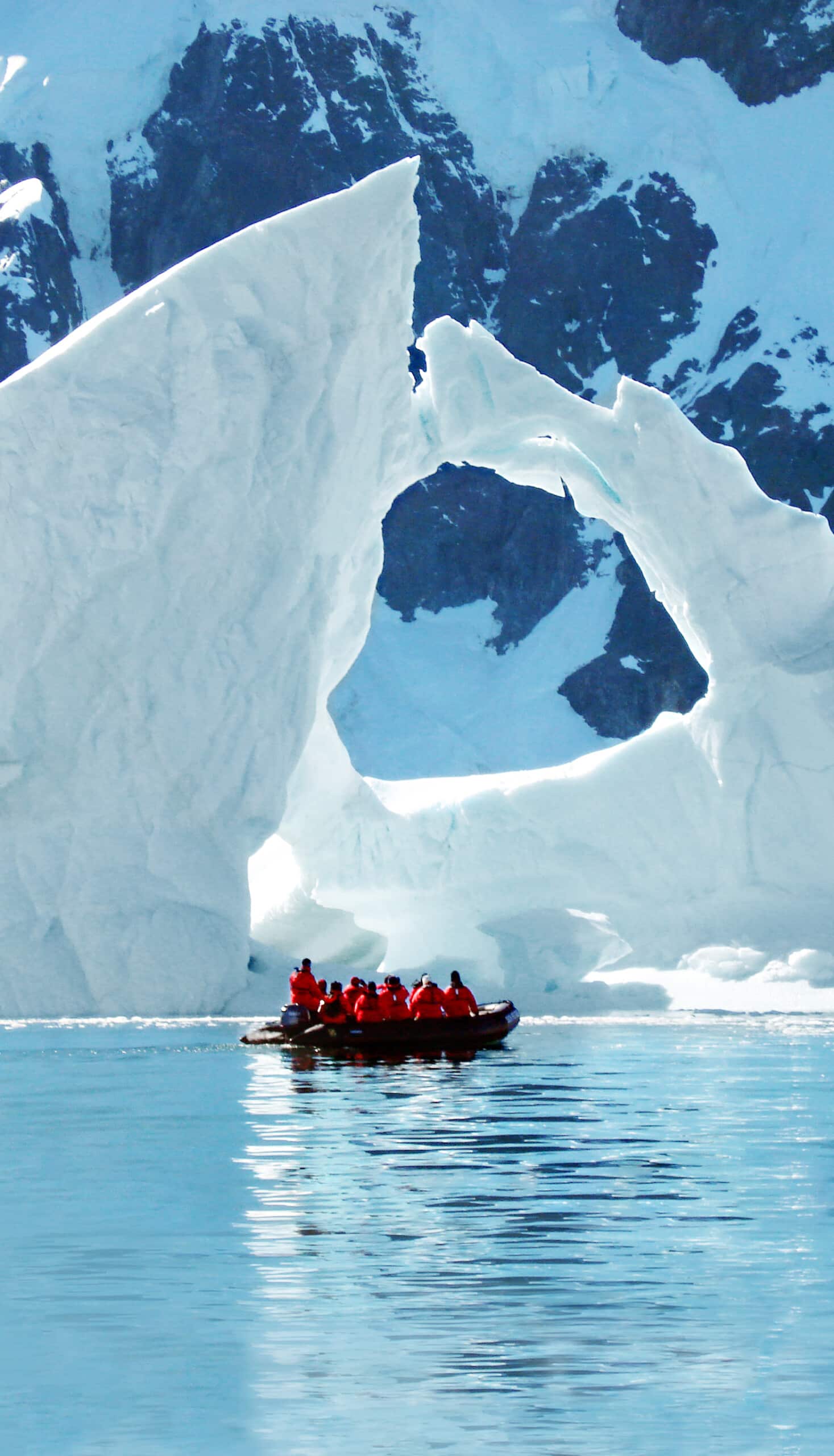 Zodiac with tourists under an iceberg in Antarctica