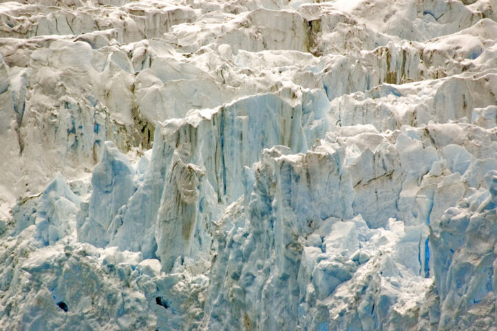 Glacier ice formations with rugged, jagged surfaces and varying shades of blue and white, resembling a true blue icebreaker.