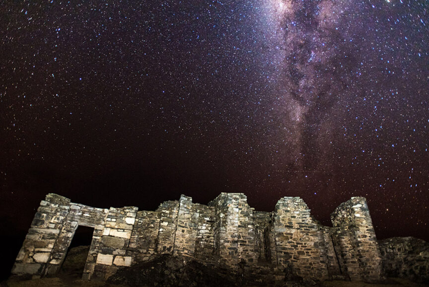 Ancient stone ruins of Choquequirao under a star-filled night sky with the Milky Way clearly visible above evoke a sense of awe.