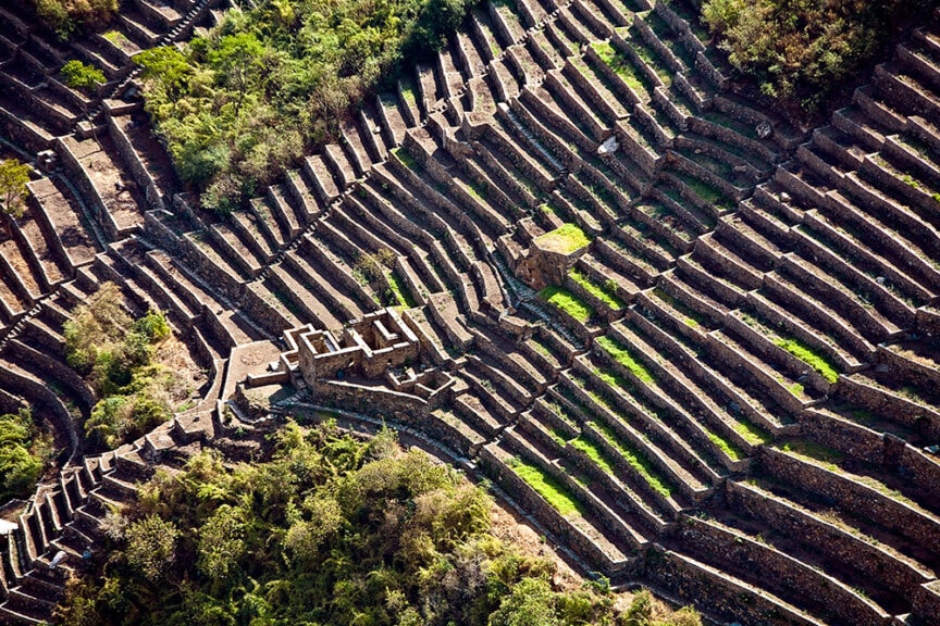 Aerial view of ancient terraced agricultural fields with stone walls, surrounded by lush greenery—truly one of the top places to travel.