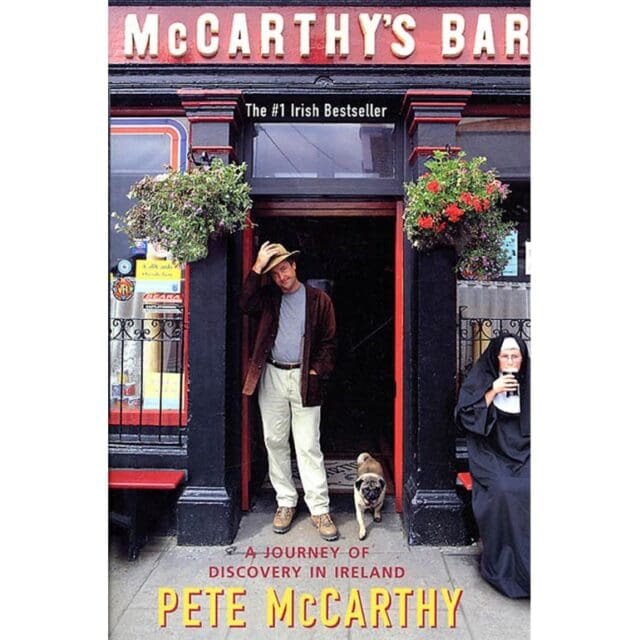 Book cover for "McCarthy's Bar" by Pete McCarthy showing a man standing in front of a bar entrance with a small dog and a nun seated nearby. The text reads, "A Journey of Discovery in Ireland," making it one of the favorite adventure books for fans of travel and exploration.
