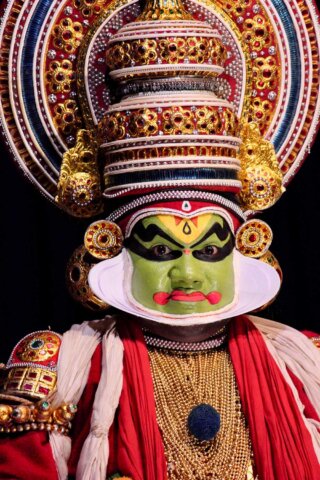 A traditional Indian Kathakali dancer from South India is shown in elaborate costume and makeup, featuring a green face, ornate headdress, and vibrant attire, creating striking portraits of cultural artistry.