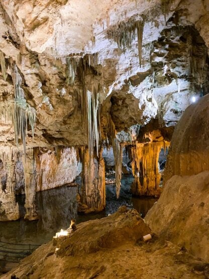 Explore the underground cave in Corsica, where stalactites and stalagmites are beautifully illuminated by artificial light, reflecting in shallow water. Perfect for those with a thirst for adventures on the islands.