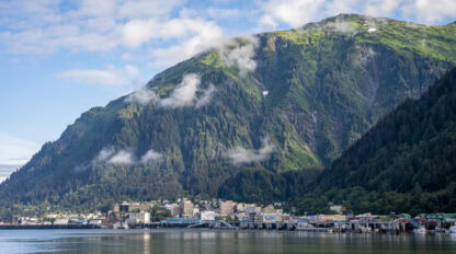 Nestled at the base of a large green mountain, Juneau offers stunning views where clouds and city reflect in calm waterfront waters—a must-see on any travel list for those seeking unique things to do.