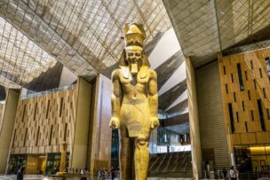 A large ancient Egyptian statue of a pharaoh stands in the spacious, modern atrium of a museum—an inspiring highlight for 2026 travel and one of the world’s must-see travel destinations.