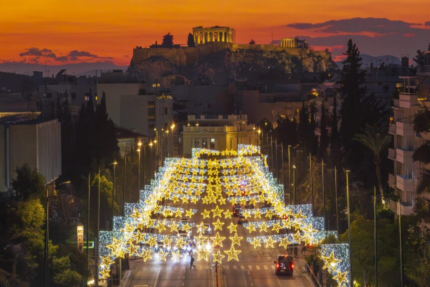 A brightly lit street with star-shaped holiday lights leads towards the Acropolis at sunset in Athens, Greece—a magical scene that reveals why winter evenings are considered the best time to visit Greece.
