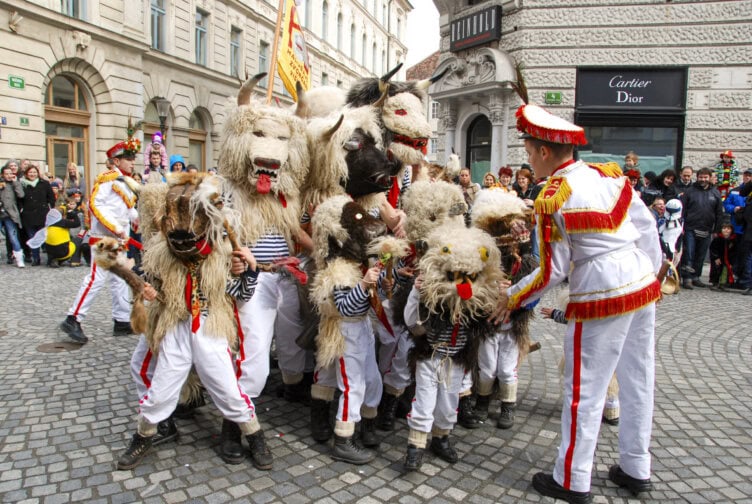 A group of people in animal costumes and white uniforms celebrating at a street festival in a European city—an unforgettable travel experience, especially if you’re exploring Croatia during the Best Time To Visit.