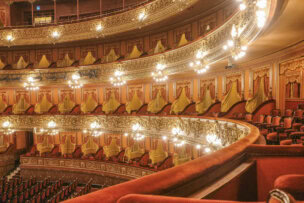 Elegant interior of a grand Buenos Aires theater with ornate balconies, red velvet seats, gold detailing, and glowing chandelier lights—a must-see among top Things to Do in Argentina.