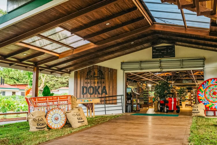Covered entrance to a shop labeled “Hacienda Doka,” with coffee sacks, colorful decorations, and souvenirs visible inside—a perfect travel stop and one of the top things to do when exploring Costa Rica.